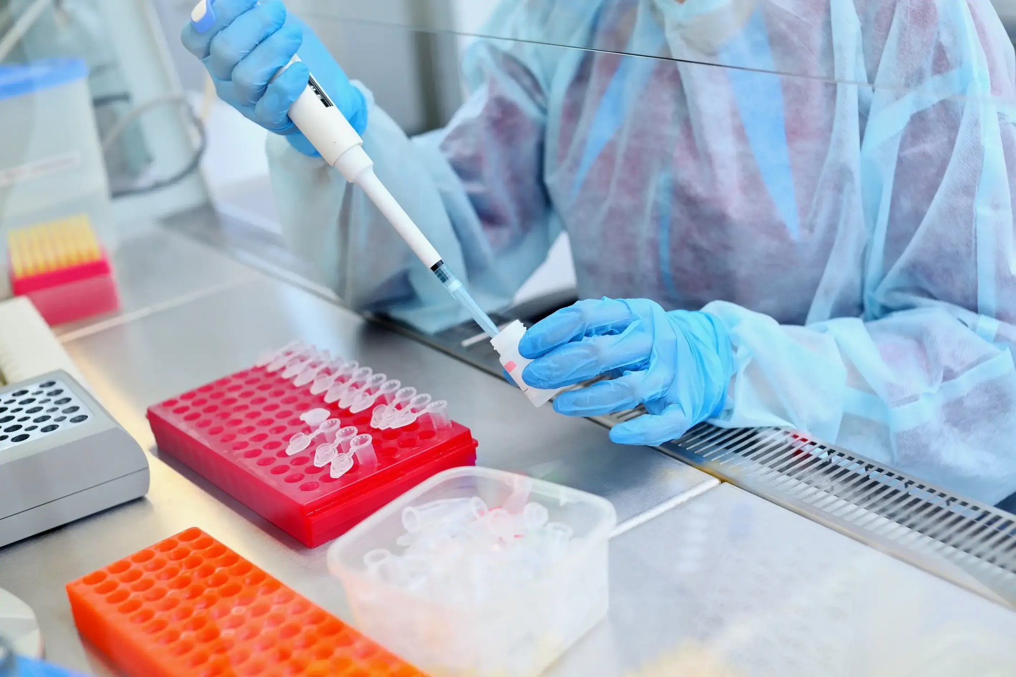 Gloved hand holding test tube near industrial water treatment facility