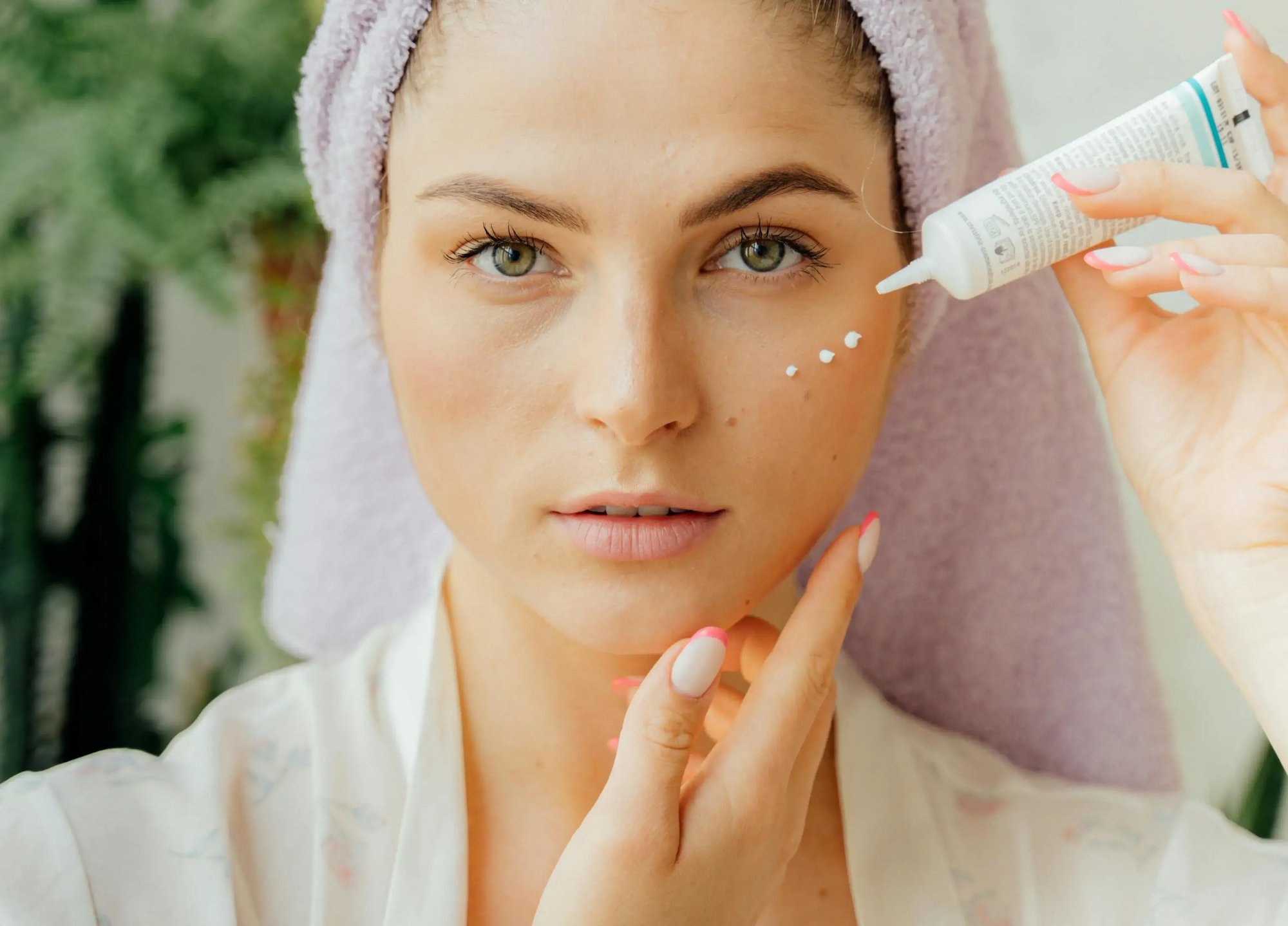 Woman applying skincare cream under her eyes